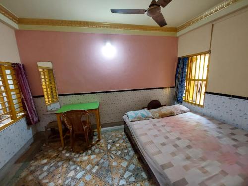 a bedroom with a bed and a table and windows at Sushamalay Guest House At Sea Beach, Puri in Puri