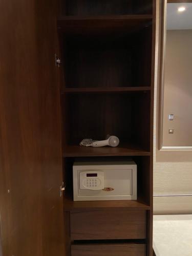 a cabinet with a clock and a microwave at Borjomi Likani Health & Spa Centre in Borjomi