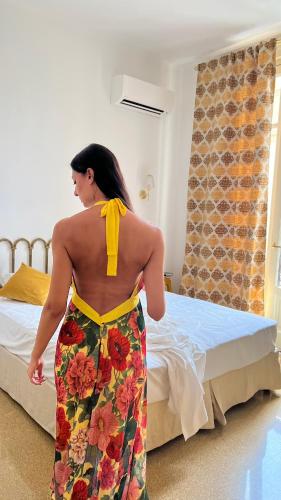 a woman in a dress standing in front of a bed at ISOLA - Smart ApartHotel in Messina