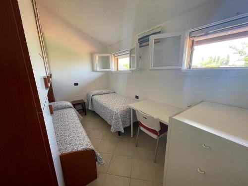 a small room with two beds and a table and chairs at Villa con porticato sul prato in Isola Albarella