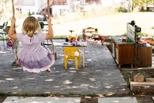 a little girl in a pink dress swinging on a swing at Michlhaus nature and suites in Aldino