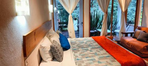 a bedroom with a bed and a couch and a window at Hotel Boutique Encino House in Valle de Bravo