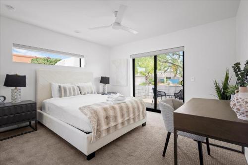 a white bedroom with a bed and a table and a desk at Horizon Heights in Scottsdale