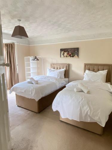 two beds sitting next to each other in a bedroom at Large Home with 5 car Parking next to Train station, Airport, NEC in Marston Green