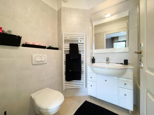 a white bathroom with a toilet and a sink at Deux pièces, parking et piscine in Beausoleil