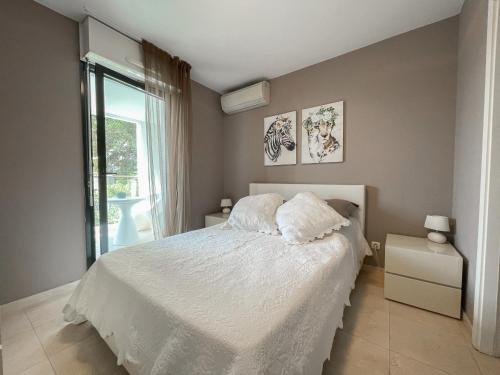 une chambre avec un lit blanc et une fenêtre dans l'établissement Deux pièces, parking et piscine, à Beausoleil