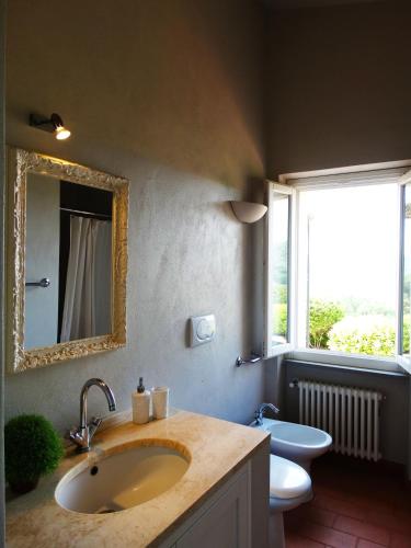 un bagno con lavandino, WC e specchio di Villa Gemma a Porto Azzurro