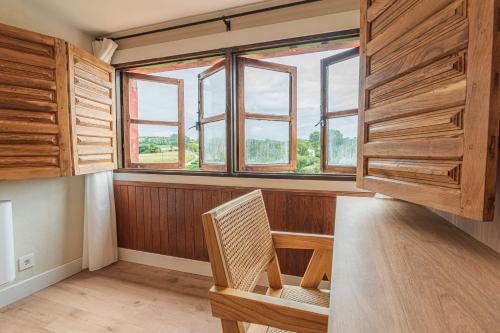 a room with a table and a chair and windows at Hotel BESTPRICE Santillana in Santillana del Mar