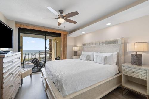 Schlafzimmer mit einem Bett, einem TV und einem Balkon in der Unterkunft Summer House 203A in Orange Beach