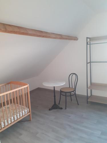 - une chambre avec un lit bébé, une table et une chaise dans l'établissement Le Gambetta, à Flixecourt