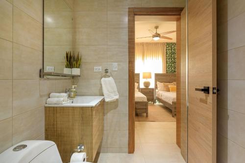 a bathroom with a sink and a toilet and a bedroom at Apartamento con piscina, gimnasio y acceso a playa in Punta Cana