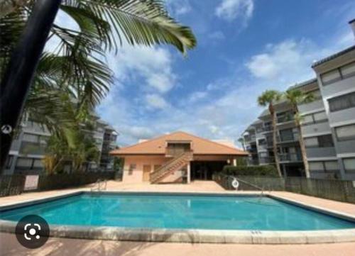 a swimming pool in front of a building with a palm tree at Amazing Guest House in West Palm Beach
