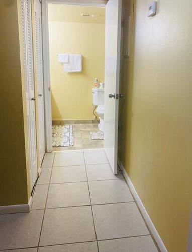 a hallway of a bathroom with a toilet and a door at Amazing Guest House in West Palm Beach