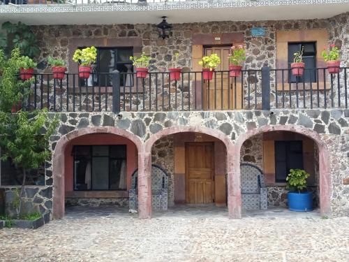 a stone building with a balcony with potted plants on it at Posada de las Monjas in San Miguel de Allende