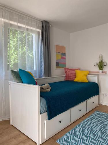 a white bed with a blue blanket and a window at Szepihenő in Balatonszepezd