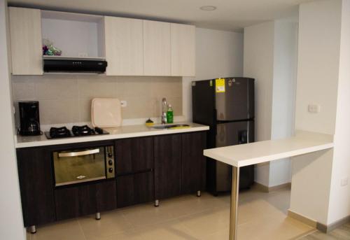 a small kitchen with a refrigerator and a sink at Apartahogar in Paipa