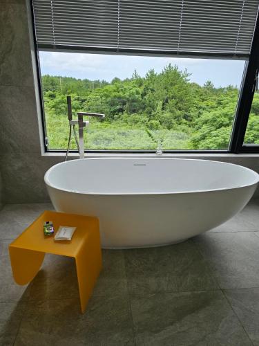 a bath tub in a bathroom with a large window at Almare Woljeong in Jeju