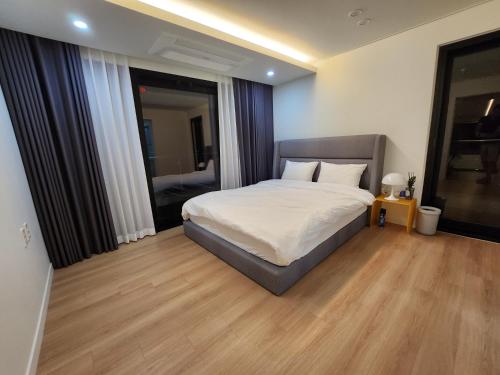 a bedroom with a bed with white sheets and wood floors at Almare Woljeong in Jeju