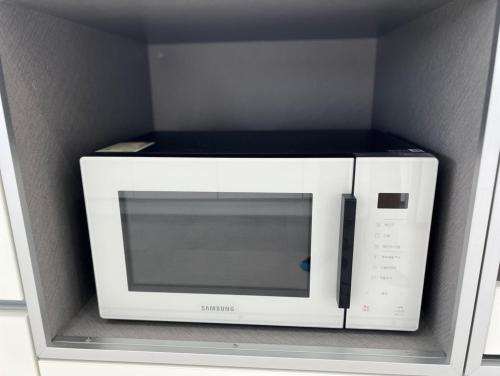 a microwave oven in a shelf in a kitchen at Almare Woljeong in Jeju