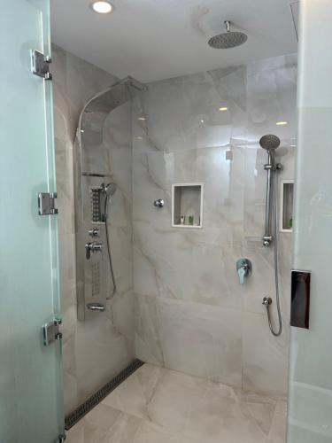 a shower with a glass door in a bathroom at فندق حدائق فرسان الفندقية in Ḩumr