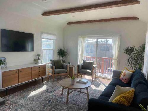 a living room with a couch and chairs and a tv at Huge Updated Spanish Apt - Steps to Beach & Bay! in Long Beach