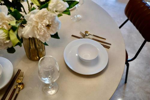 uma mesa com um prato e um vaso de flores brancas em MarQ Dic1 Hồ Chí Minh em Ho Chi Minh