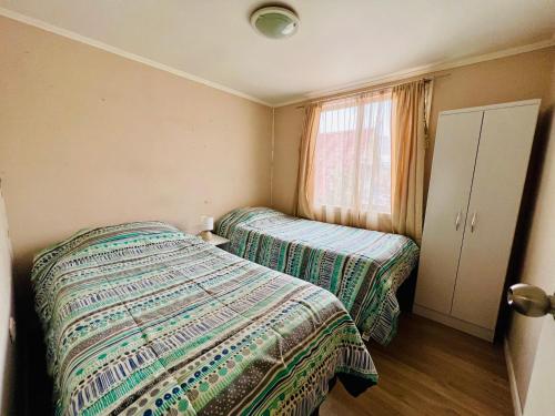 1 dormitorio con 2 camas y ventana en Casa y departamentos amoblados Talca en Talca