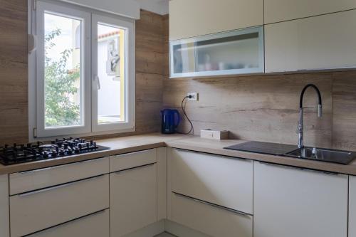 a kitchen with white cabinets and a sink and a window at Apartments Mare in Banjol