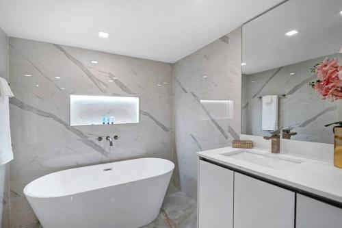 La salle de bains est pourvue d'une baignoire blanche et d'un lavabo. dans l'établissement City of Dreams! Renovated With Water & Park Views, à Miami