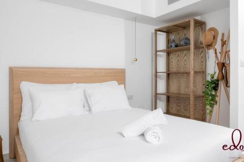 een slaapkamer met een wit bed en een boekenplank bij דירה מהפנטת במתחם סי סייד 100 מטר מהים - By Edom in Eilat