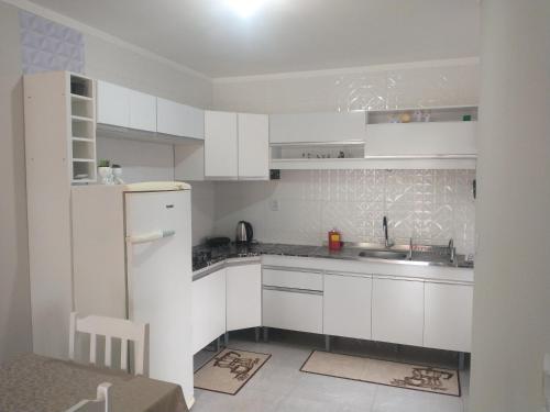 una cucina bianca con lavandino e frigorifero di Residencial Adventus II a Venâncio Aires