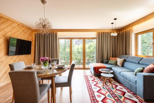 ein Wohnzimmer mit einem blauen Sofa und einem Tisch in der Unterkunft Apartamenty Blisko TATR Zakopane in Zakopane