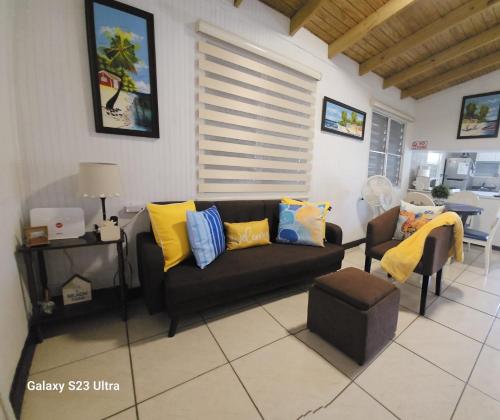 a living room with a black couch and yellow pillows at Casita Playera Aguadeña 