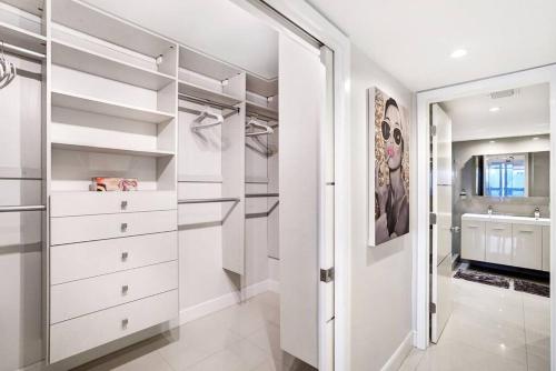 a walk in closet with white cabinets and a sink at Some Like It Hot! Miami Skyline & Water Views 4BR in Miami