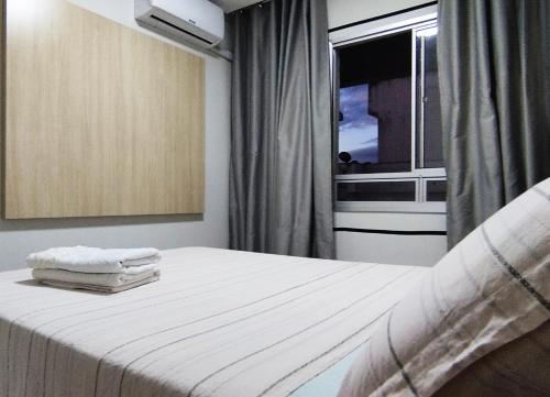 Schlafzimmer mit einem Bett mit weißer Bettwäsche und einem Fenster in der Unterkunft Top Place in Vitória