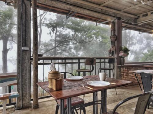 a wooden table and chairs on a screened in porch at Baan Nhuer Mek บ้านเหนือเมฆ Coffee and Desk on the Cloud in Ban Pang Klang