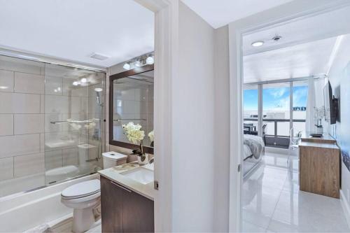 a bathroom with a toilet and a tub and a sink at Champagne & Ice! Water Views, 2 Private Balconies! in Miami