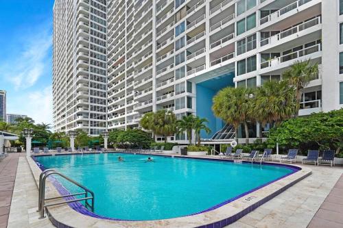 a large swimming pool in front of a large building at Champagne & Ice! Water Views, 2 Private Balconies! in Miami