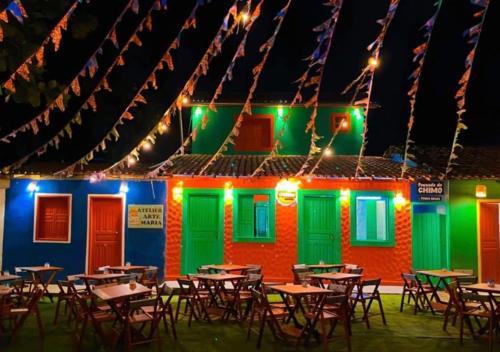 a restaurant with tables in front of a building with lights at Pousada Crocodilo Caraíva in Caraíva