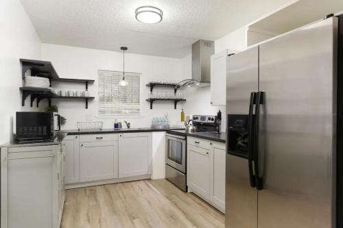 a kitchen with white cabinets and a stainless steel refrigerator at 10 Min to Sea World & Lackland, Pets OK, Sleeps 12 in San Antonio