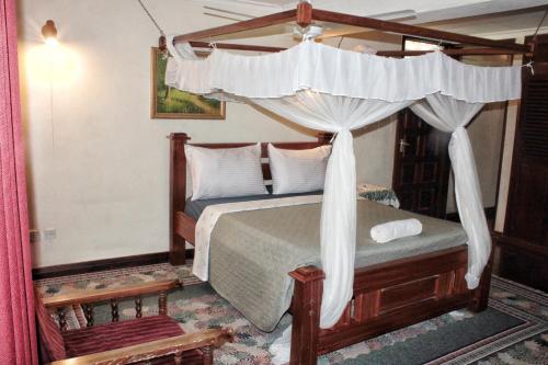 The Embassy Residence في مومباسا: غرفة نوم مع سرير مظلة مع ستائر بيضاء