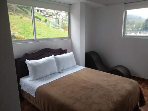 een slaapkamer met een groot bed en 2 ramen bij HOTEL DIAMOND in Gachancipá