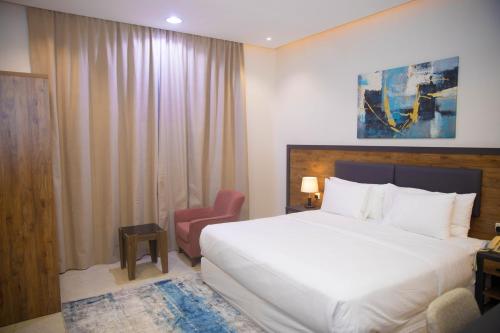 a bedroom with a large white bed and a red chair at نوفا بارك للشقق المخدومة in Sharurah