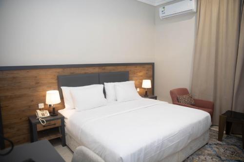 a hotel room with a white bed and a chair at نوفا بارك للشقق المخدومة in Sharurah
