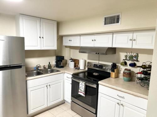 a kitchen with white cabinets and a stove and a sink at Minutes to the River Walk and the Alamo Pet Friendly Sleeps 8! in San Antonio