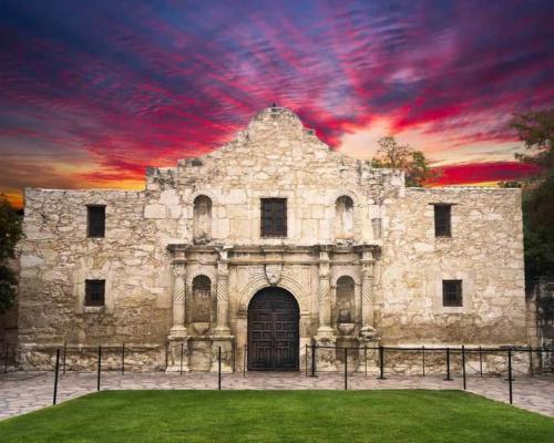 un antiguo edificio de piedra con una puesta de sol en el fondo en Minutes to the River Walk and the Alamo Pet Friendly Sleeps 8!, en San Antonio