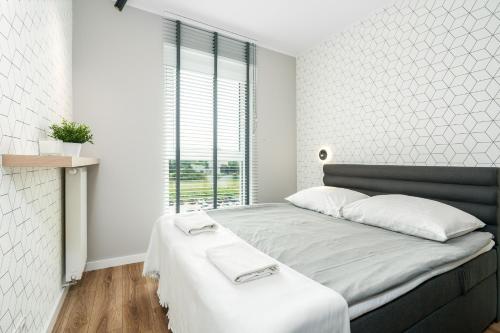 a bedroom with a large bed with a white wall at Riverside Apartments by KRAMM in Poznań
