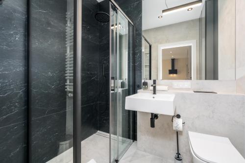 a bathroom with a sink and a shower at Riverside Apartments by KRAMM in Poznań