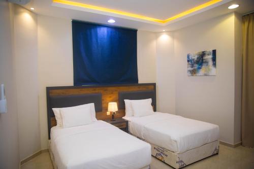 two beds in a room with a blue curtain at نوفا بارك للشقق المخدومة in Sharurah