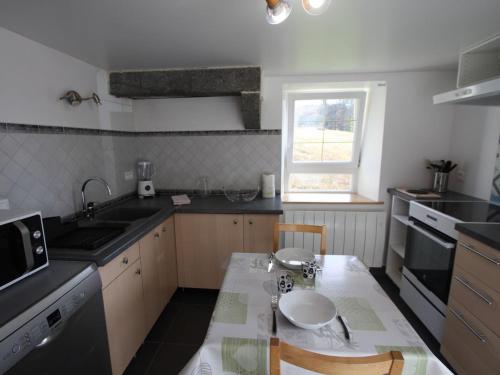 une cuisine avec une table, un évier et une fenêtre dans l'établissement Charmant gîte en montagne, 3 étoiles, proche randonnées et Alsace, tout confort avec terrasse. - FR-1-589-391, à Rupt-sur-Moselle